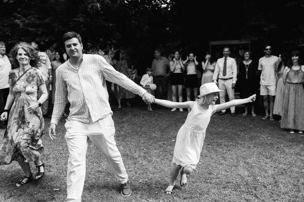 Kind zieht den Bräutigam am Anzug bei Gartenhochzeit