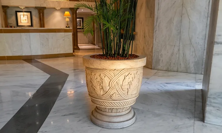 Hand-carved stone planter with floral relief in a marble-floored hotel lobby
