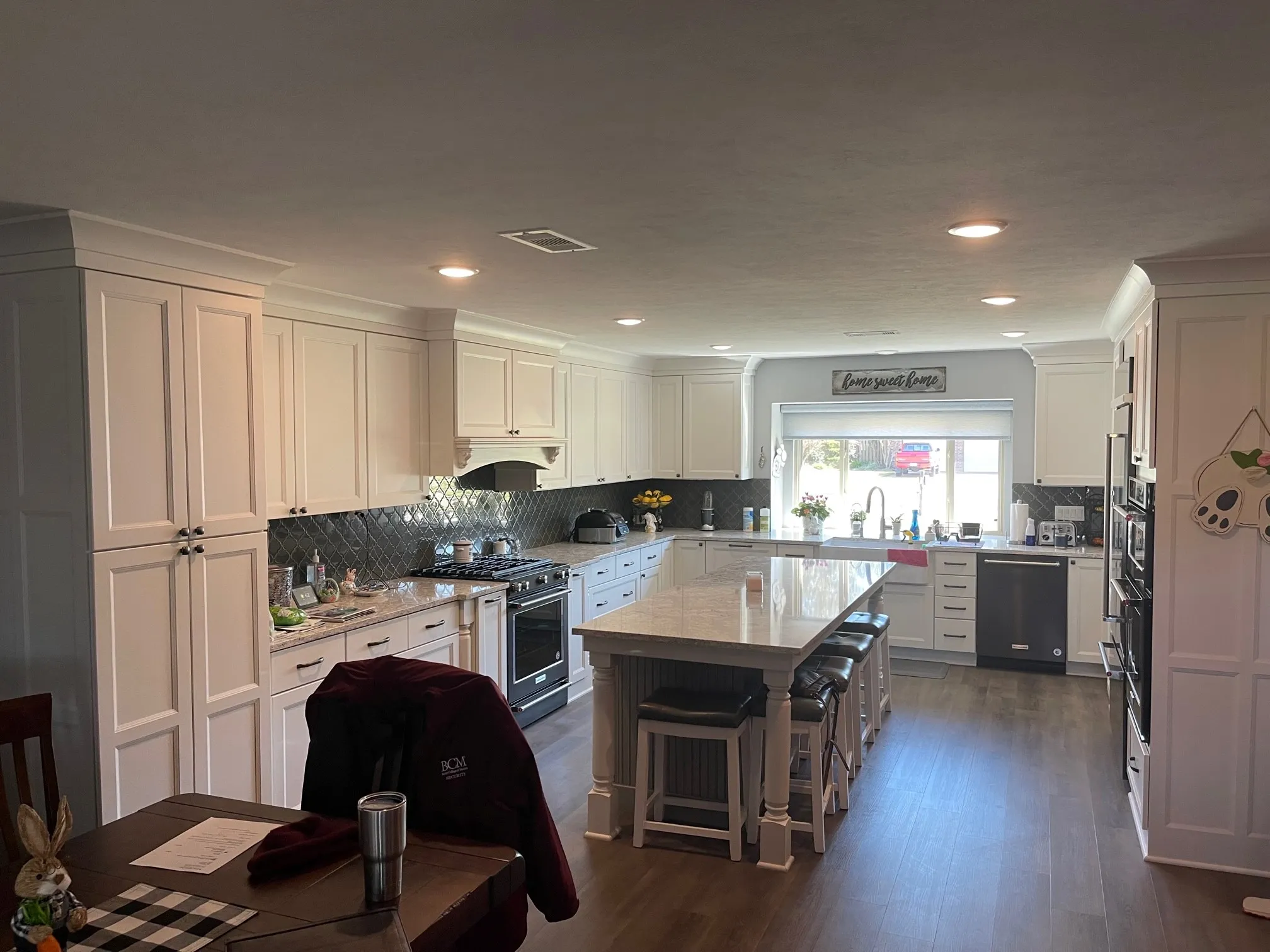 Modern kitchen with white cabinets, large island with stools, and a window over the sink.