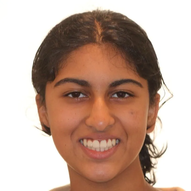 Smiling young person with dark hair pulled back against a white background.