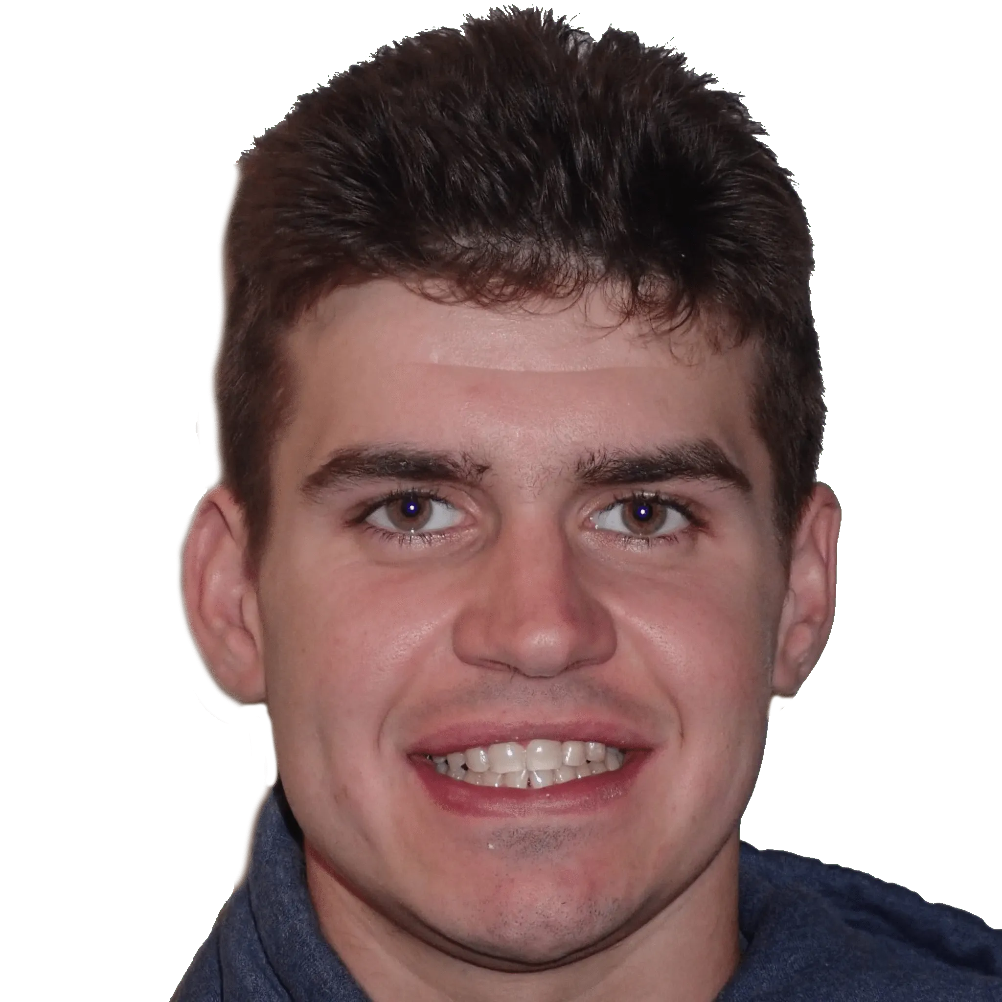 Smiling young man with short dark hair wearing a blue shirt against a green background.