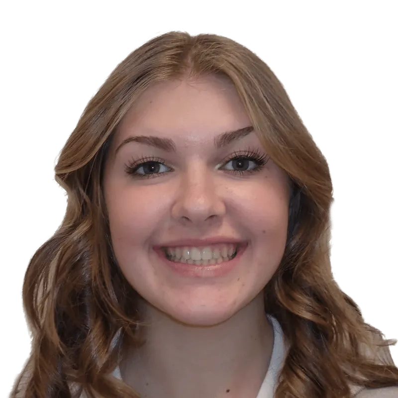 Smiling young woman with wavy light brown hair and visible teeth, looking straight ahead.