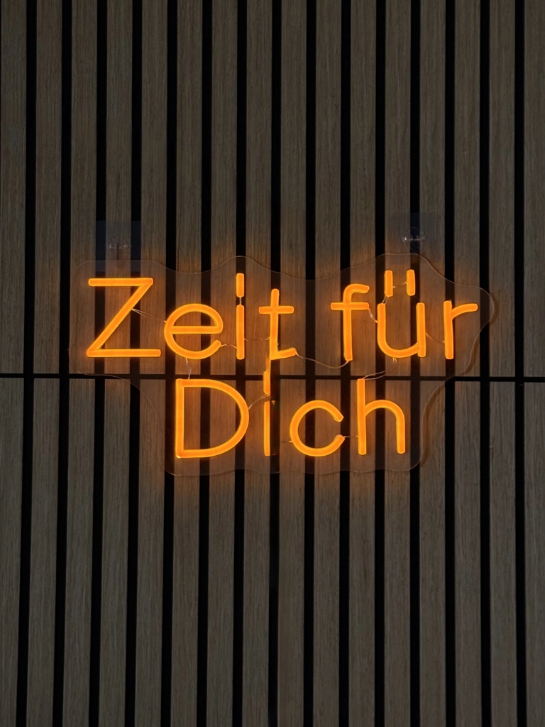 Neonschriftzug „Zeit für Dich" an der Holzlamellenwand im Wellness- & Sportmassage Studio von Denys Polieshchuk in Kassel