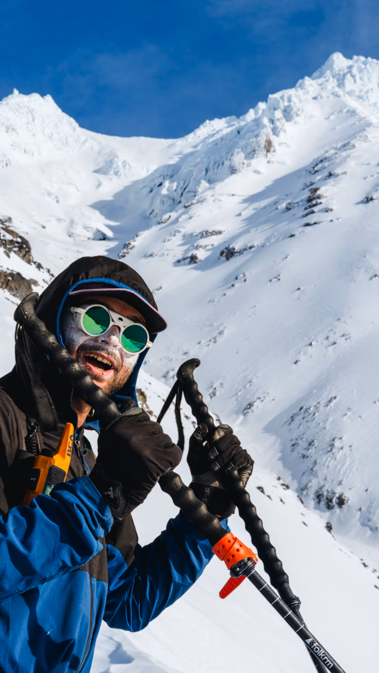 Stratton geared up on a steep snowy backcountry slope with mountains behind him.