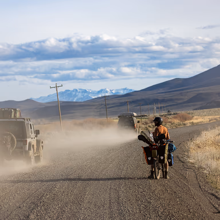 Stratton biking a remote desert highway with his snowboard gear strapped to his bike.
