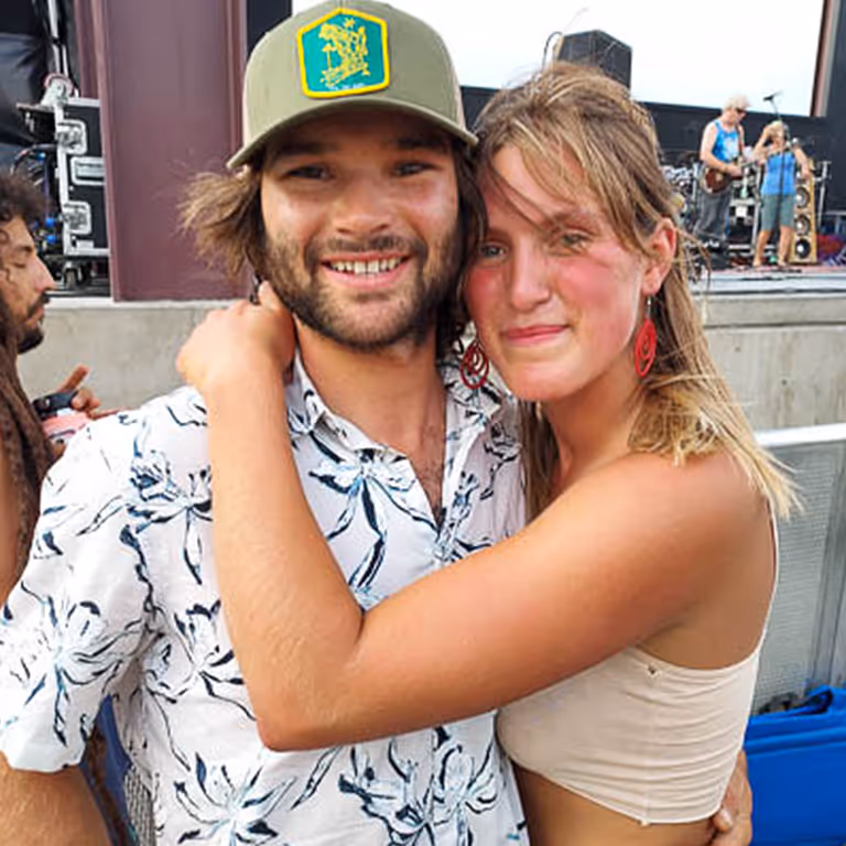 Stratton and his partner Madeline smiling together at an outdoor concert.