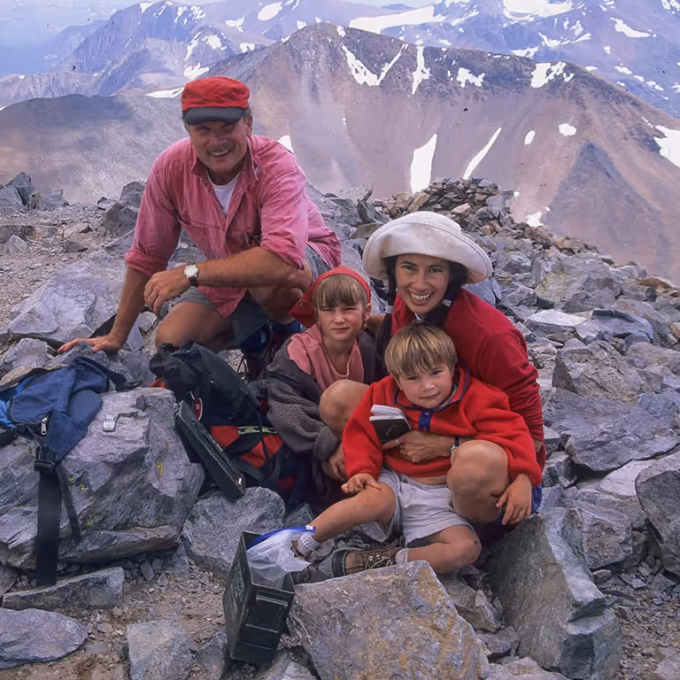 Stratton and his family posing together on a rocky mountain summit.