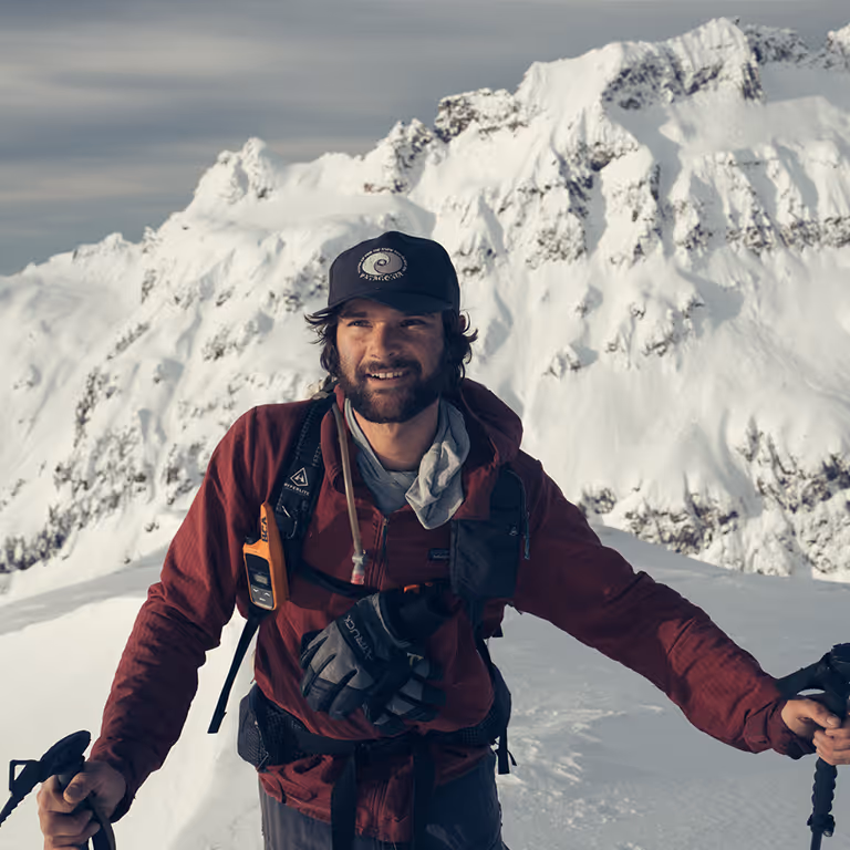 Stratton smiling on a snowy backcountry ridge with his splitboard poles near Mount Baker.