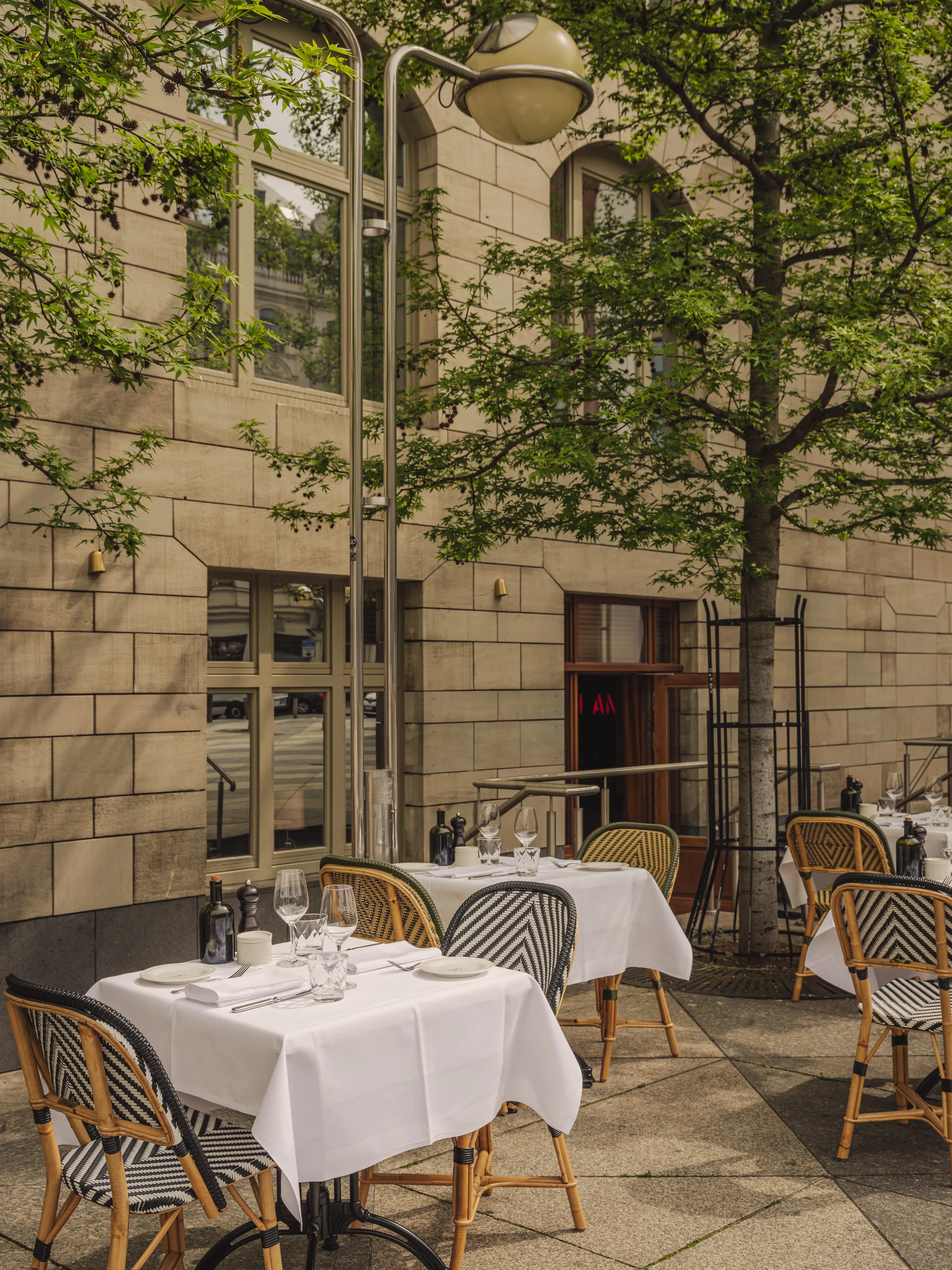 Sommertag auf der Terrasse des Le Petit Royal Frankfurt mit gedeckten Tischen unter Bäumen