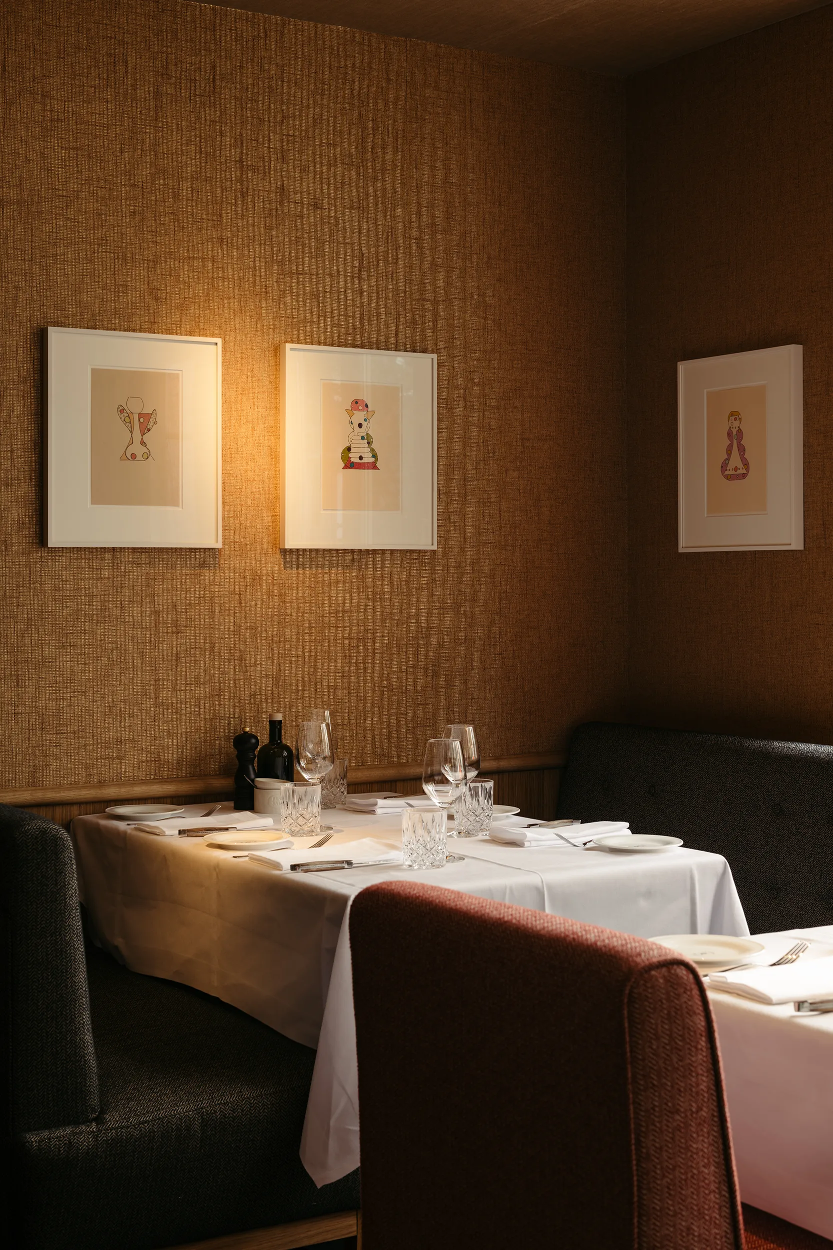Intim gedeckter Tisch im Le Petit Royal Frankfurt mit warmem Licht und Kunstwerken an der Wand