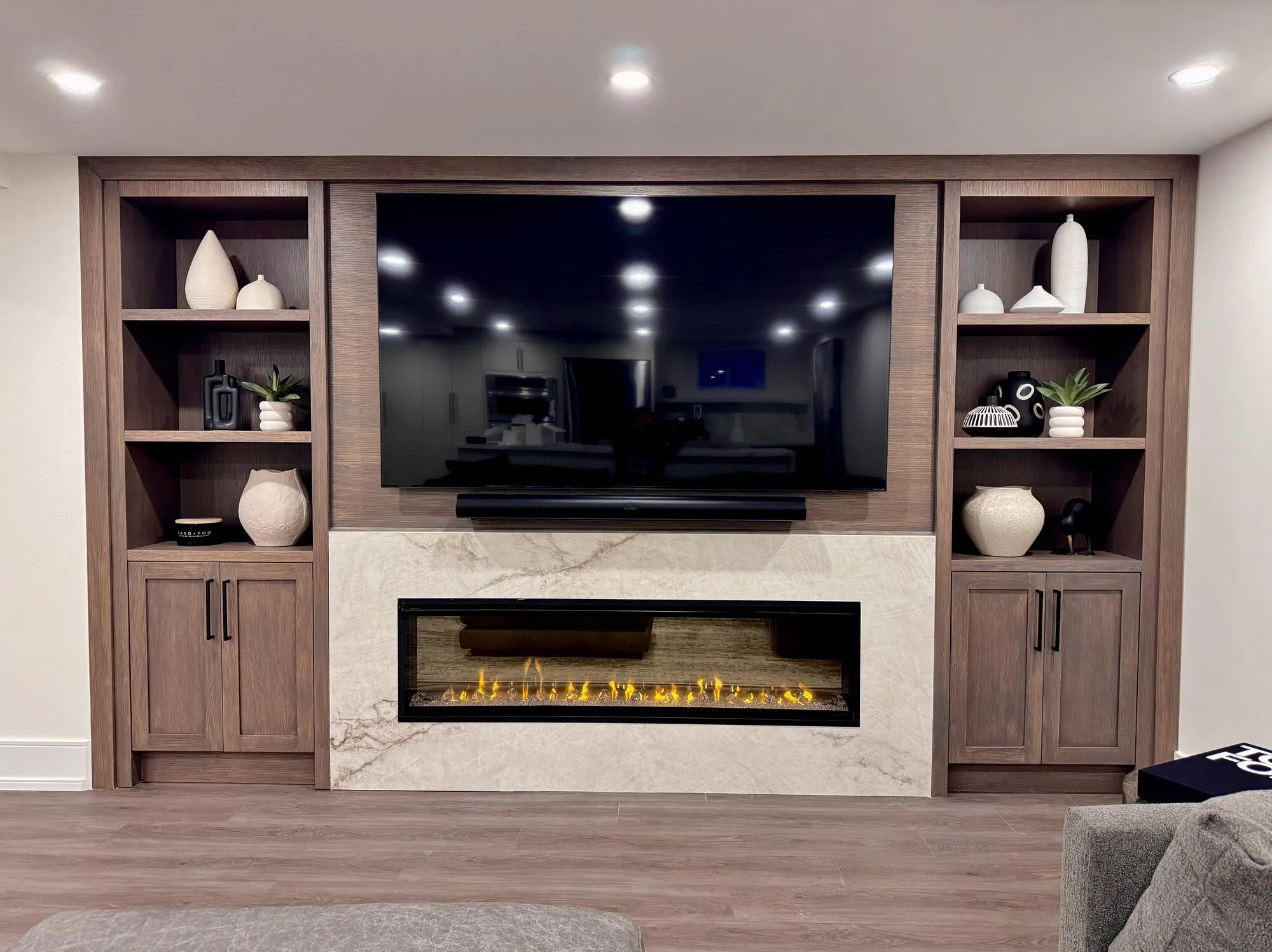 Custom walnut media wall with marble fireplace surround — real Desire Basements project, GTA