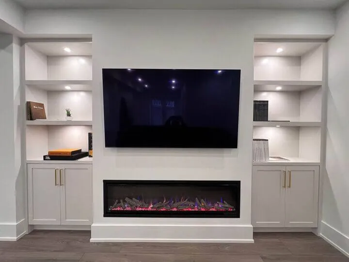 A Basement Living room showcasing the Basement Renovation Finishes with a focus on custom fireplace, custom wall cabinets with potlights, TV mount, and custom hardwood flooring