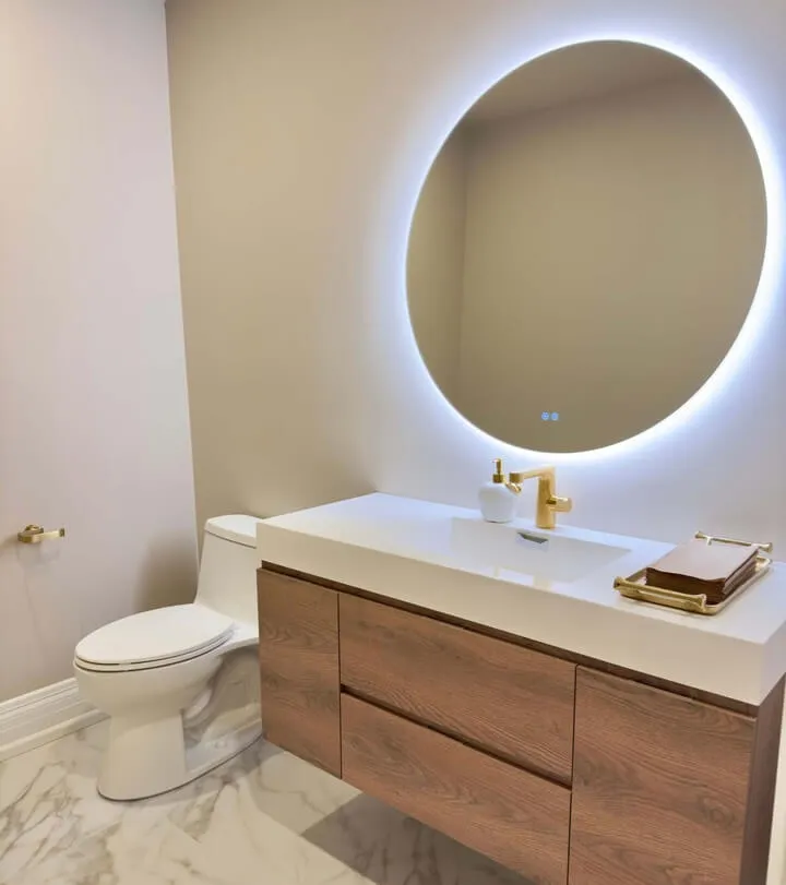 Basement Bathroom Renovation Showcasing ccustom sink, toilet, mirror with lighting, and custom gold faucets