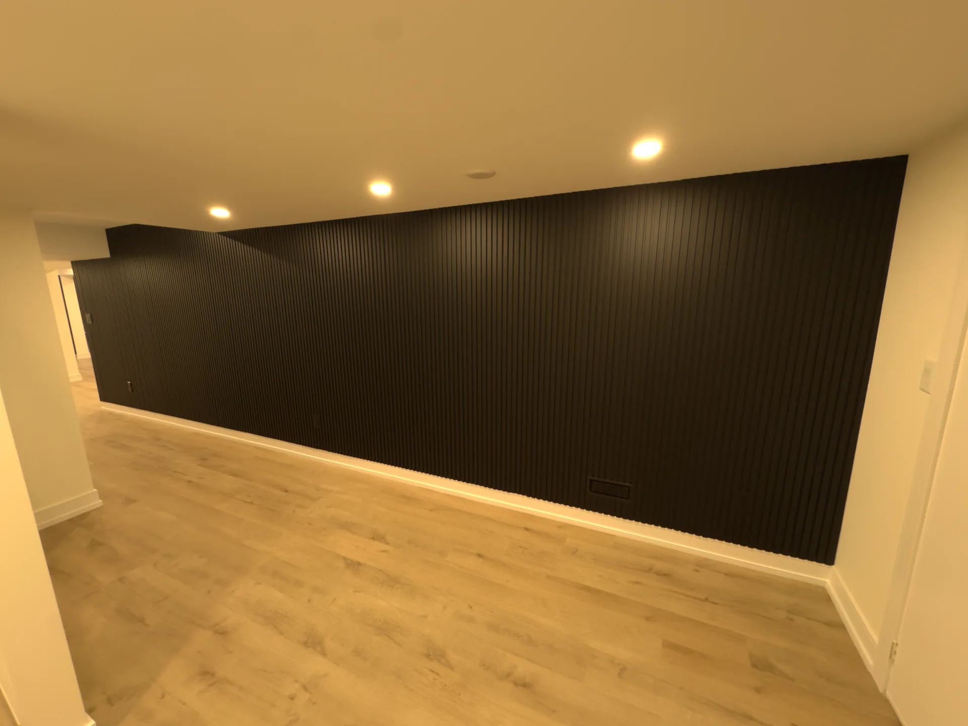 Basement finishing in Toronto — black slat accent wall in a basement media room