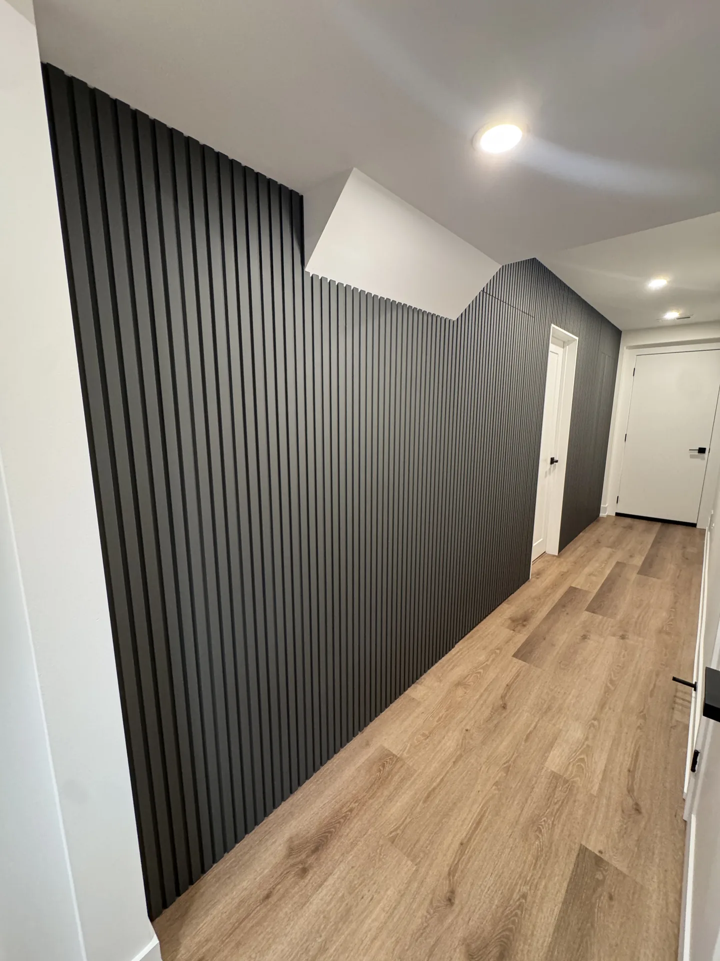 Structural work in Mississauga — black wood slat feature wall along a finished basement hallway