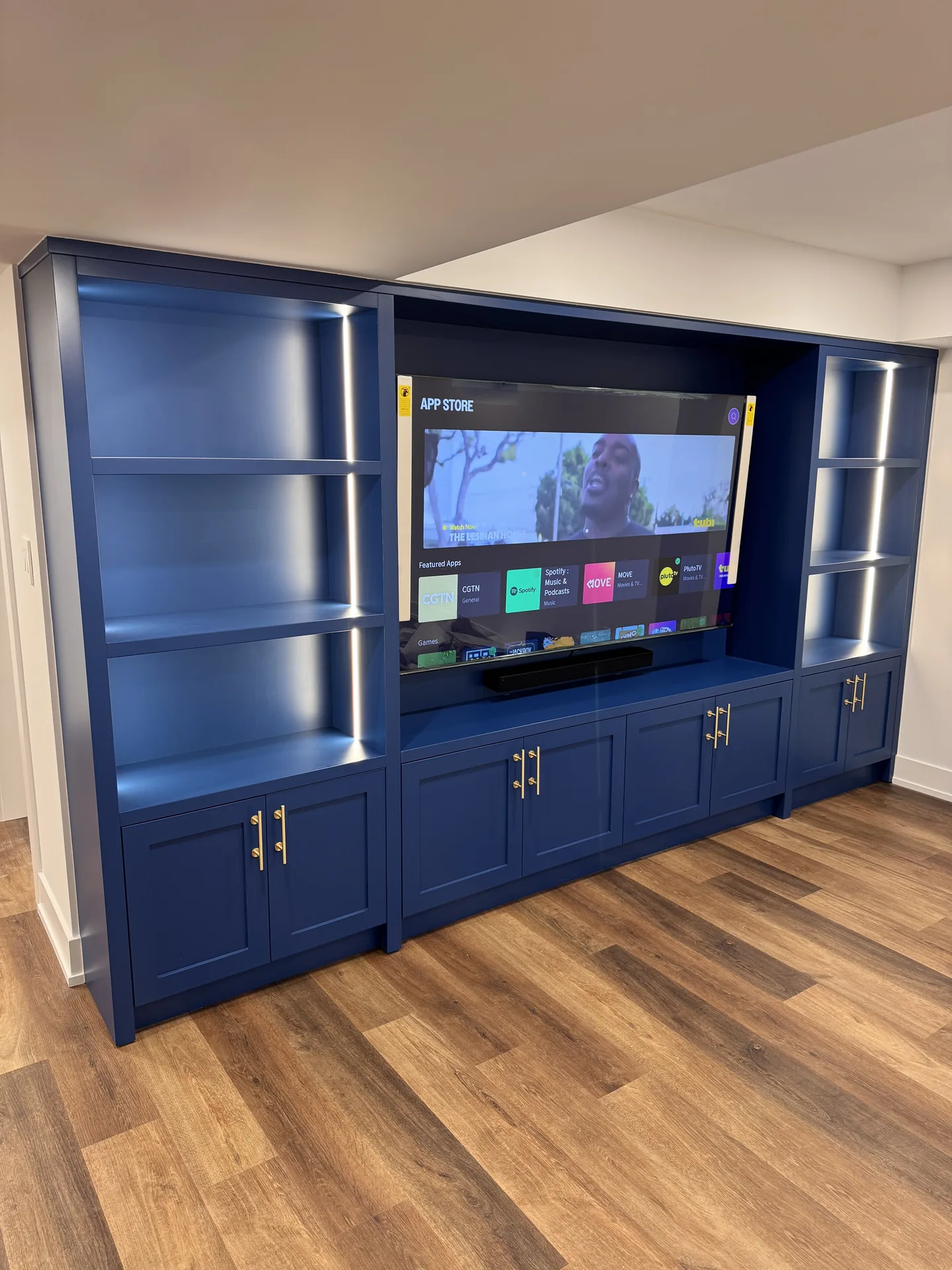 Basement finishing in Scarborough — blue basement TV wall with LED shelving and cabinets