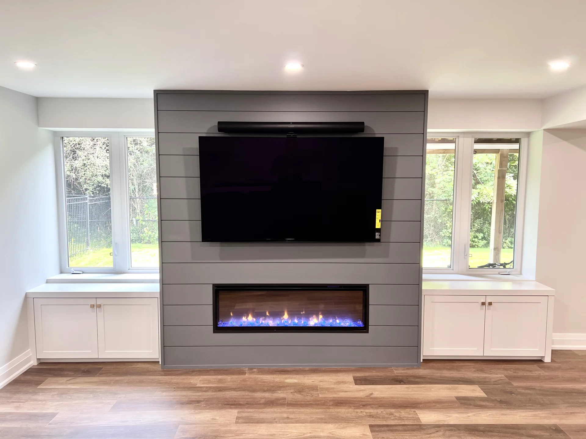Basement finishing in Brampton — grey basement fireplace TV wall between windows