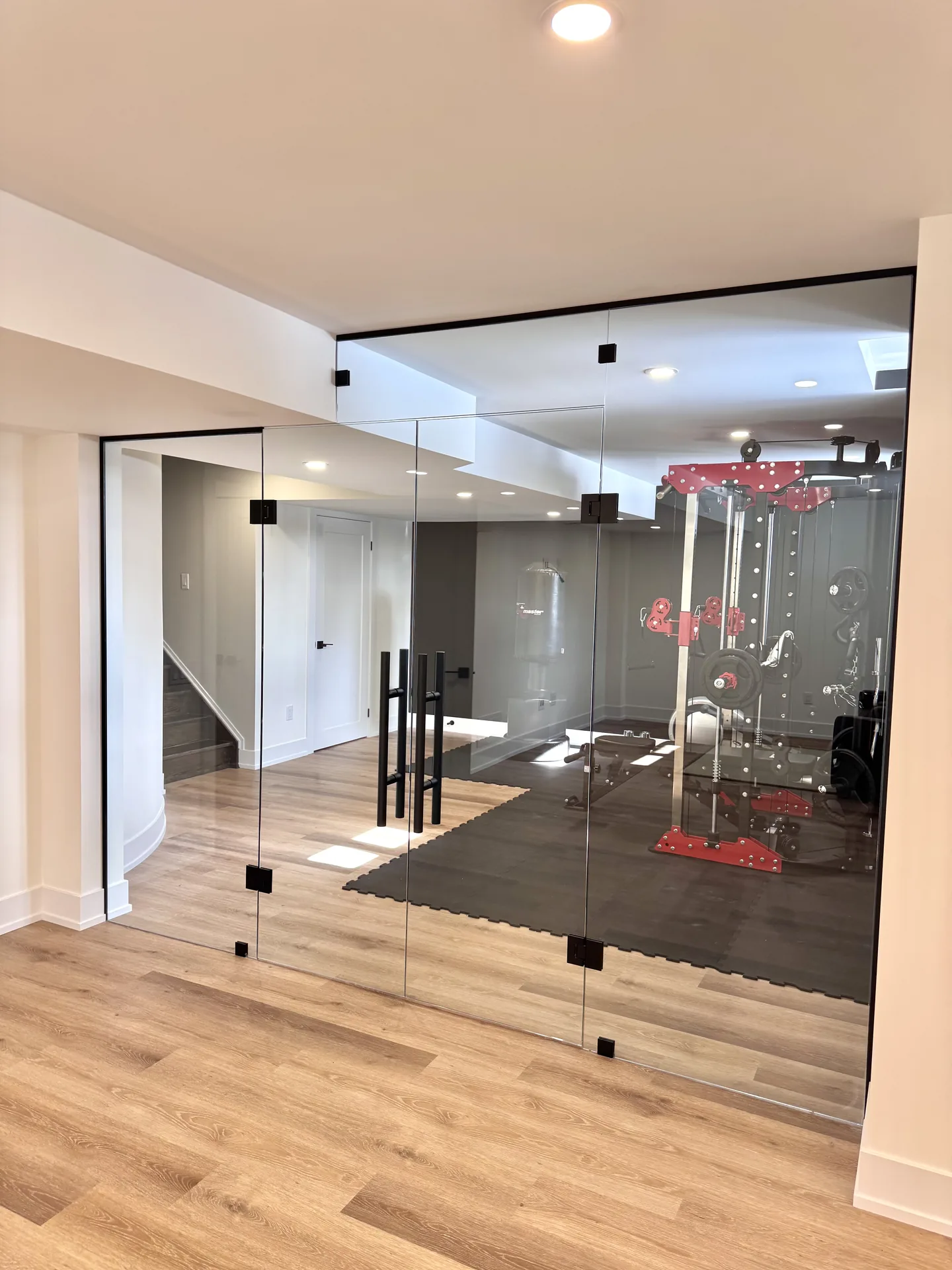 Structural work in Aurora — basement gym behind glass wall with red equipment