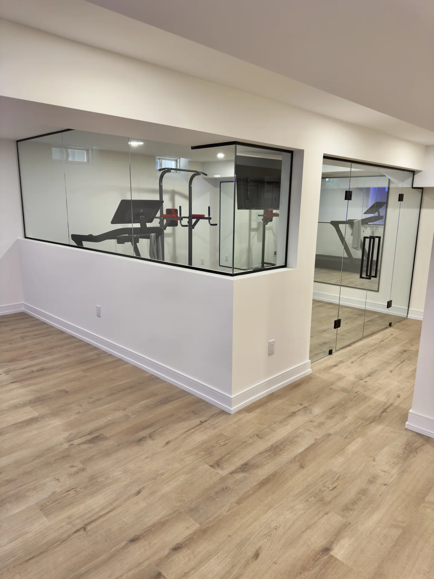 Structural work in Newmarket — bright basement gym with mirror wall and white interior