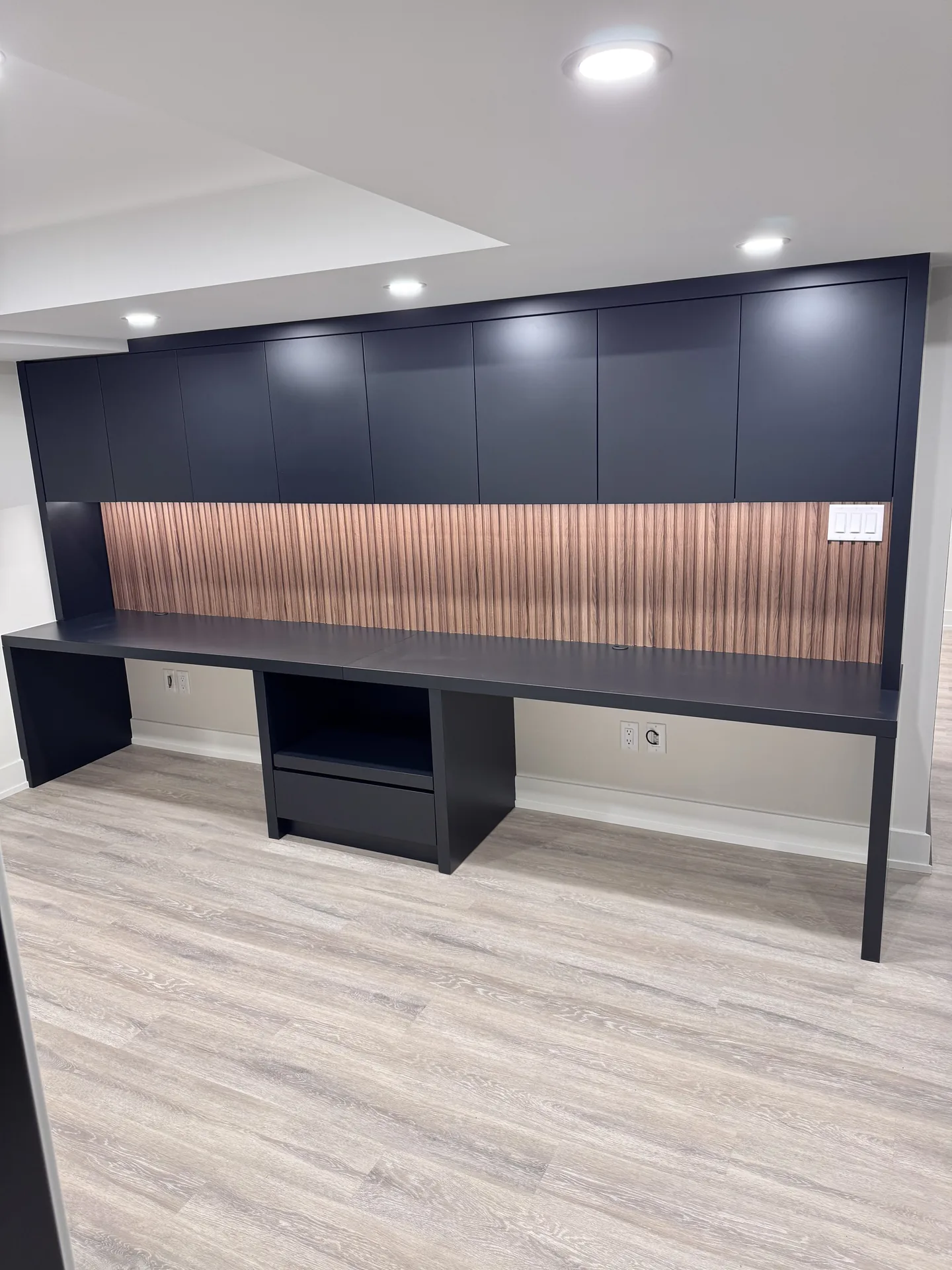 Home renovations in East Gwillimbury — custom basement home office desk unit with walnut slat backing and lit shelving