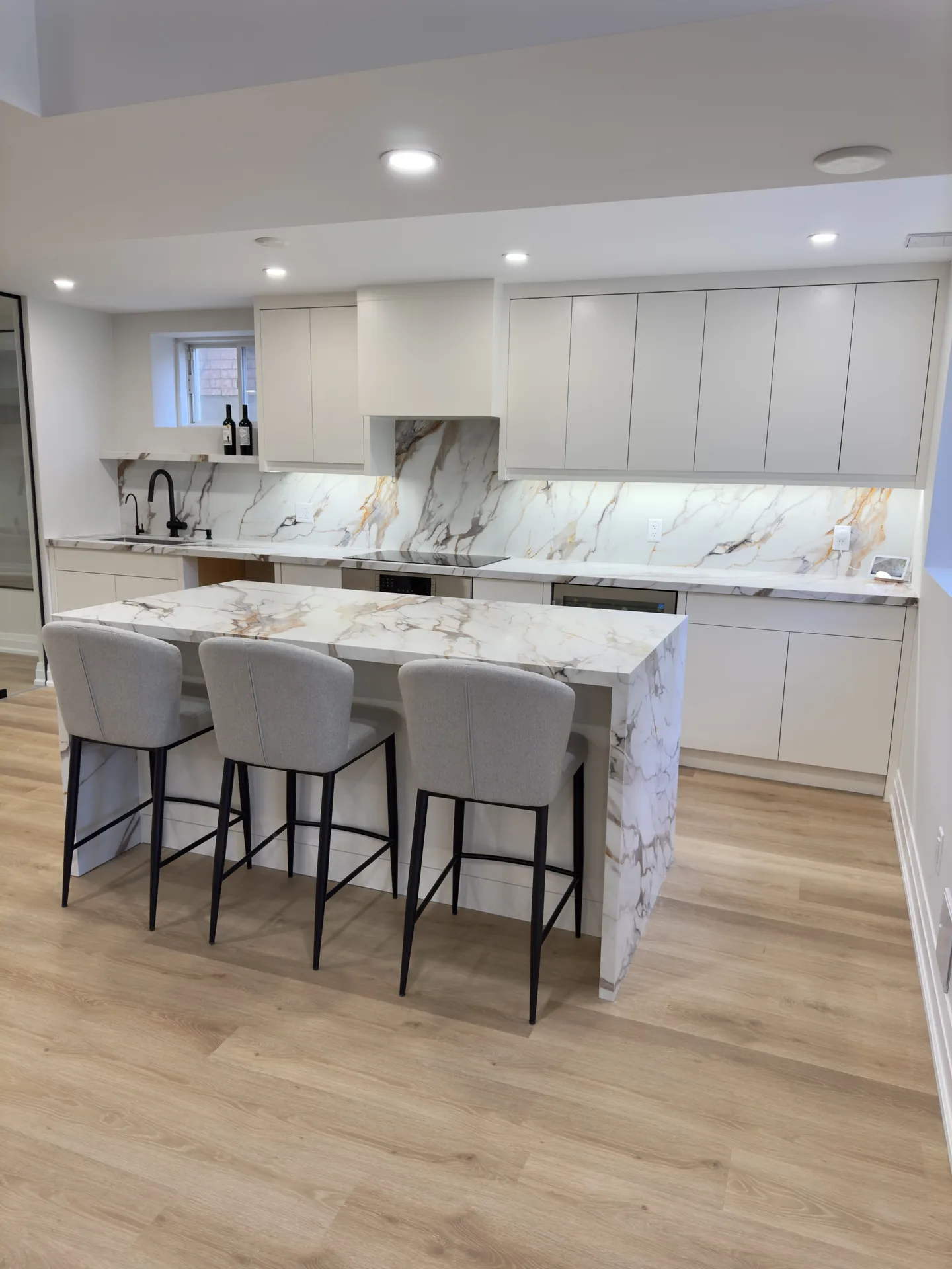Home renovations in Innisfil — basement kitchen with marble island and grey stools