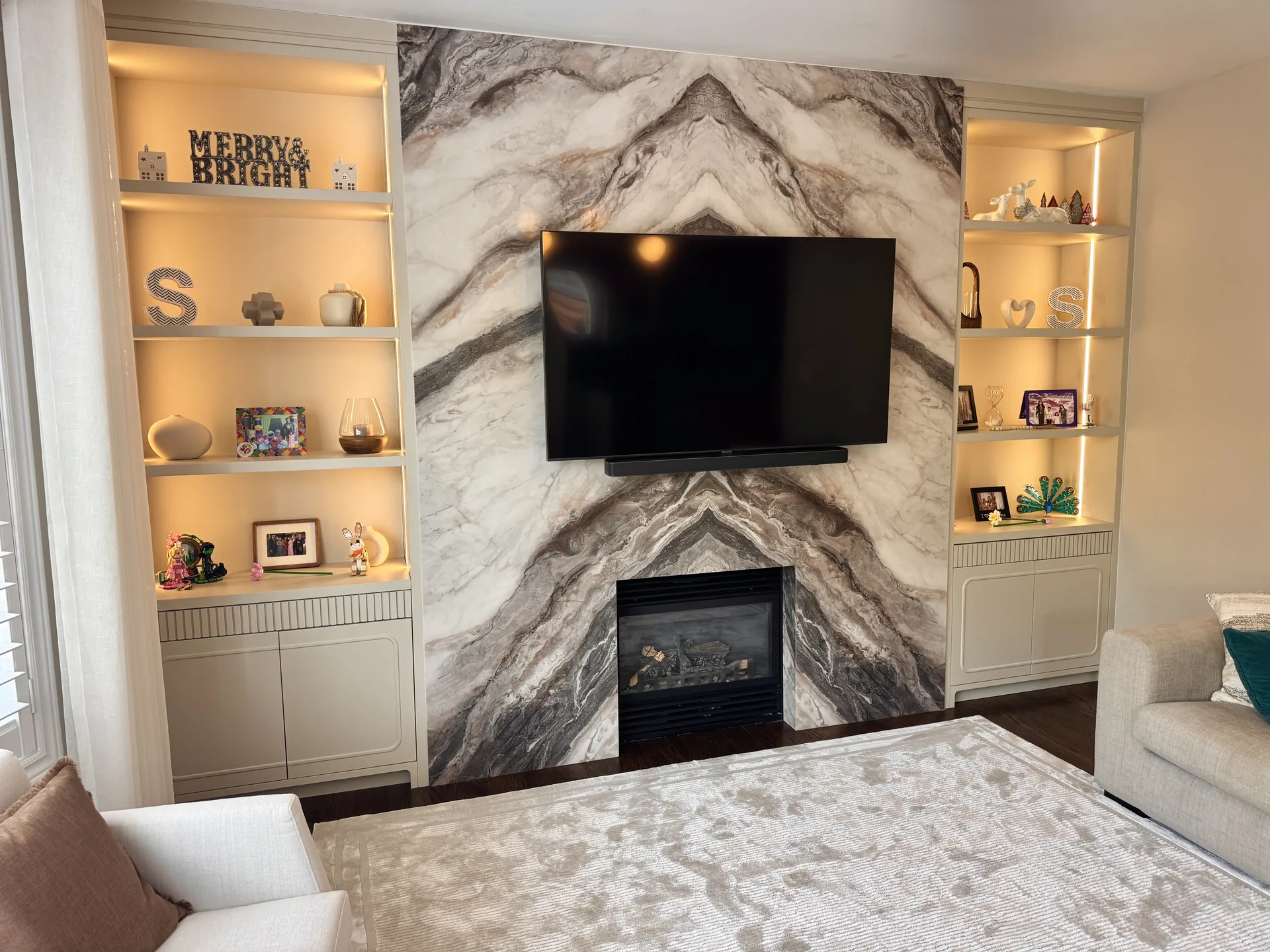 Basement finishing in Kleinburg — marble fireplace media wall with lit built-ins in a finished basement