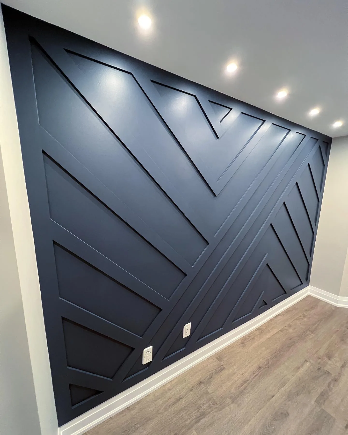 Structural work in Bradford — navy geometric trim accent wall in a finished basement