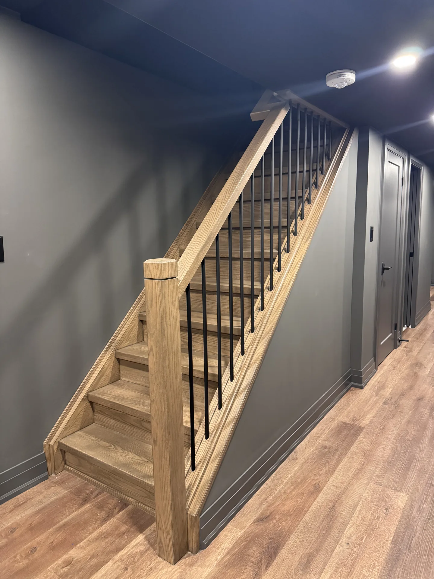 Structural work in Barrie — oak basement staircase with metal spindles and dark walls