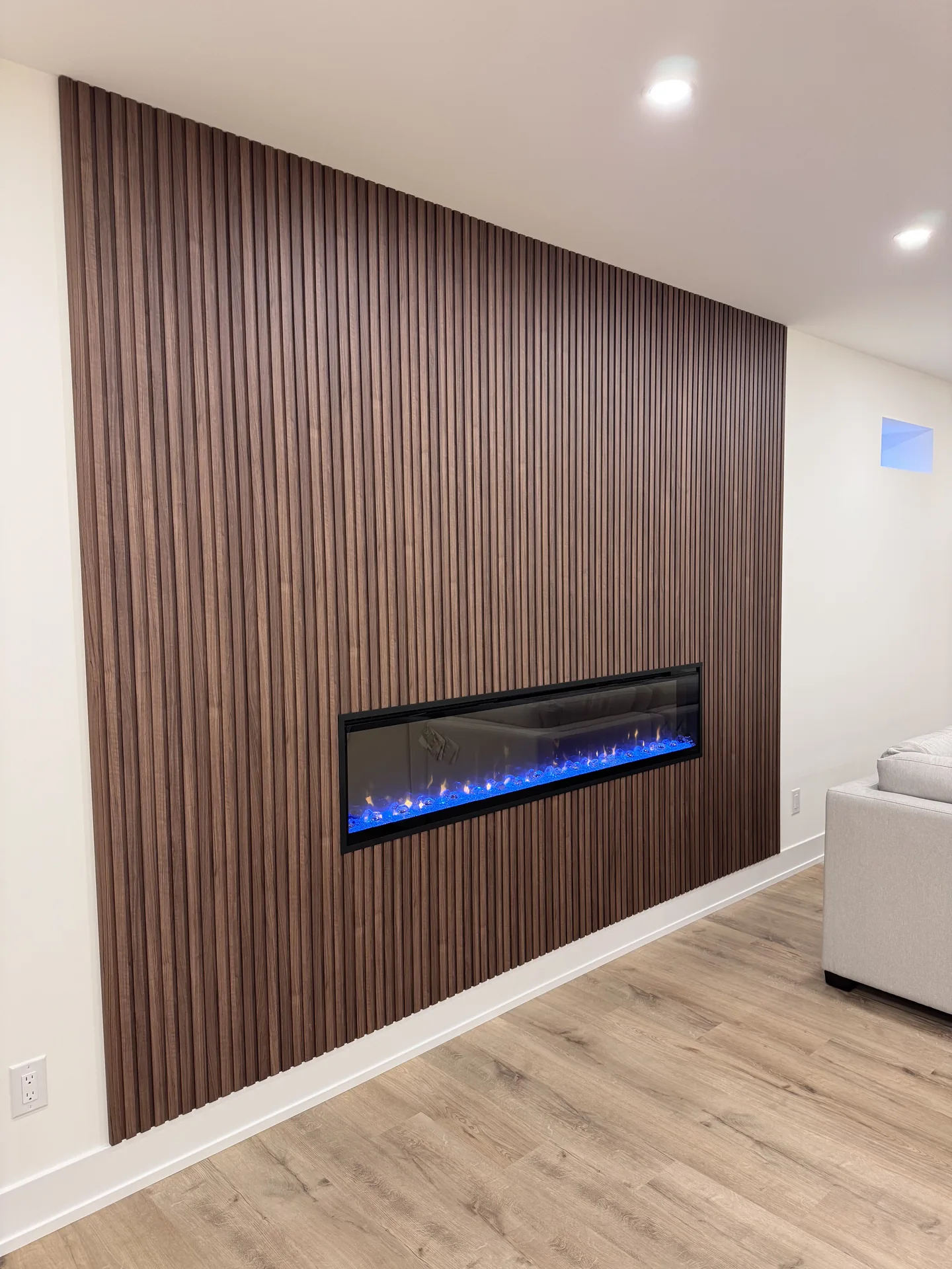 Walnut slat feature wall with linear fireplace — basement renovation in Etobicoke by Desire Basements
