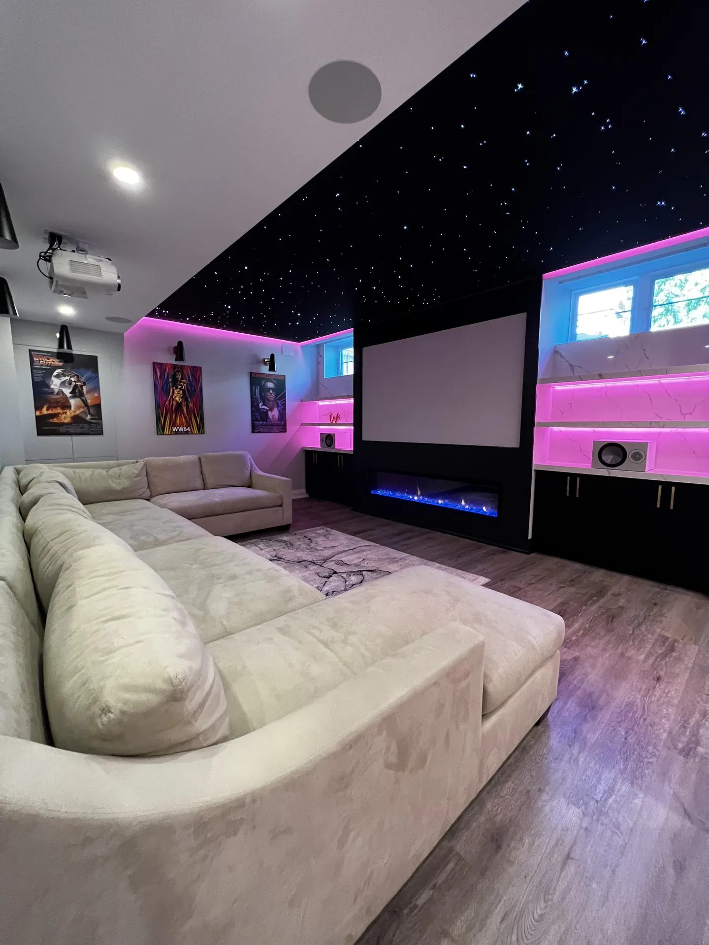 Basement theatre with star ceiling, pink LED accents and projector screen — basement renovation in Burlington by Desire Basements