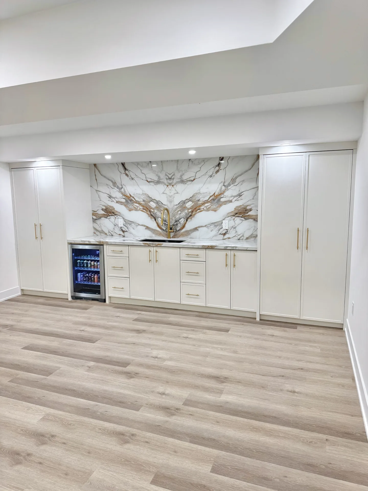 White basement bar with marble feature wall — basement renovation in Kleinburg by Desire Basements
