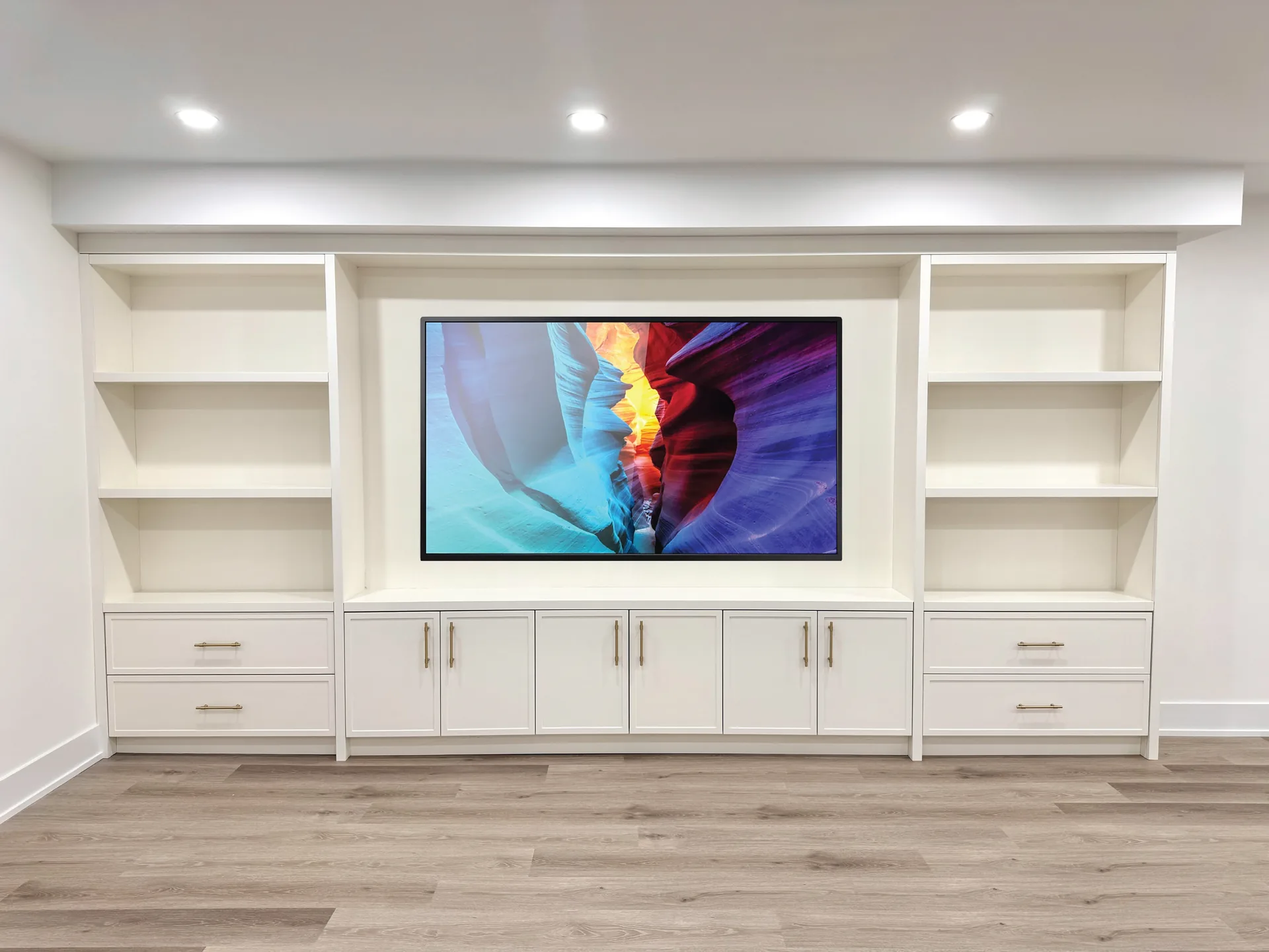 White basement media wall with built-in cabinets — basement renovation in Milton by Desire Basements