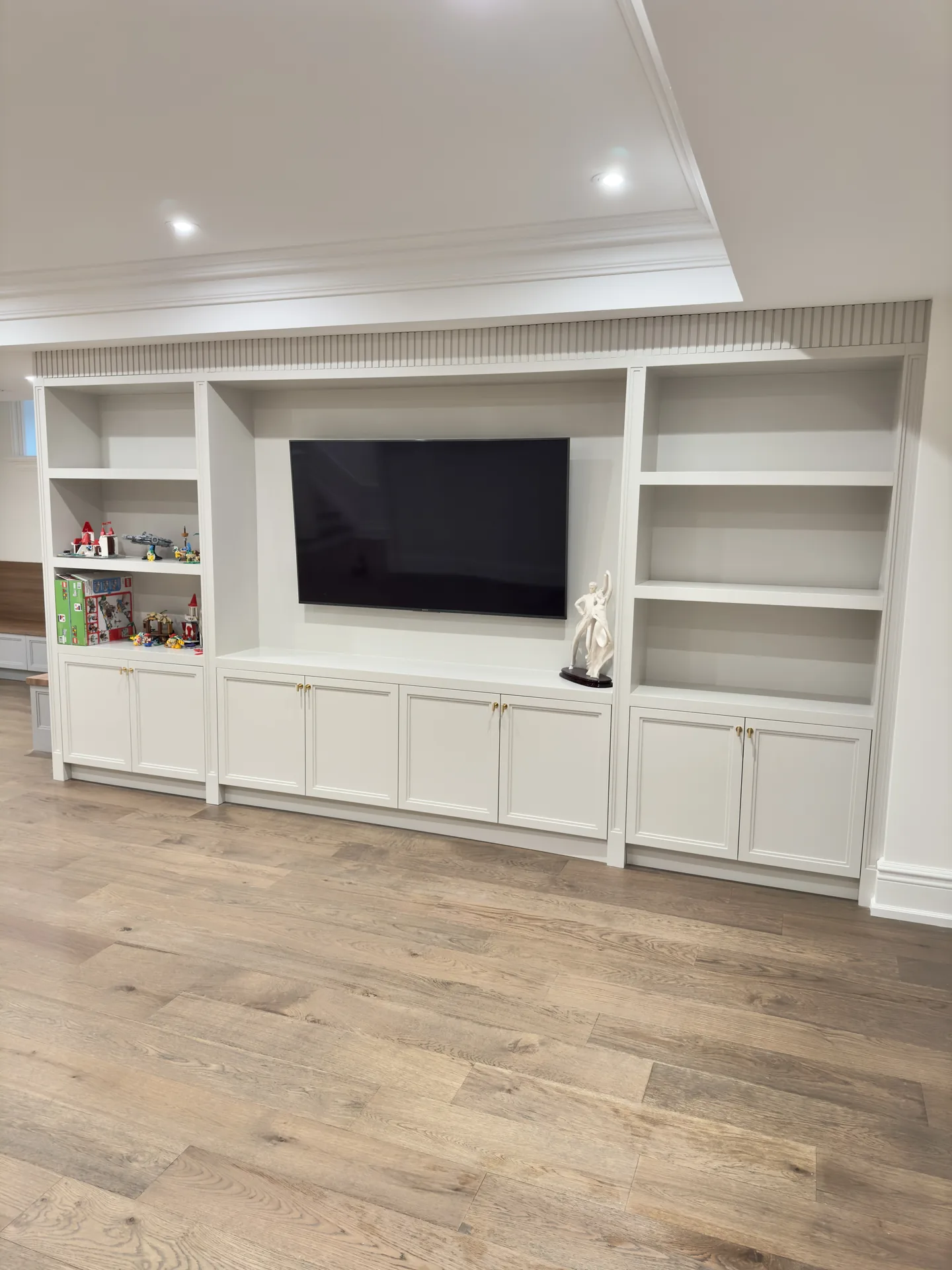 White basement TV wall with crown moulding and built-ins — basement renovation in Ajax by Desire Basements