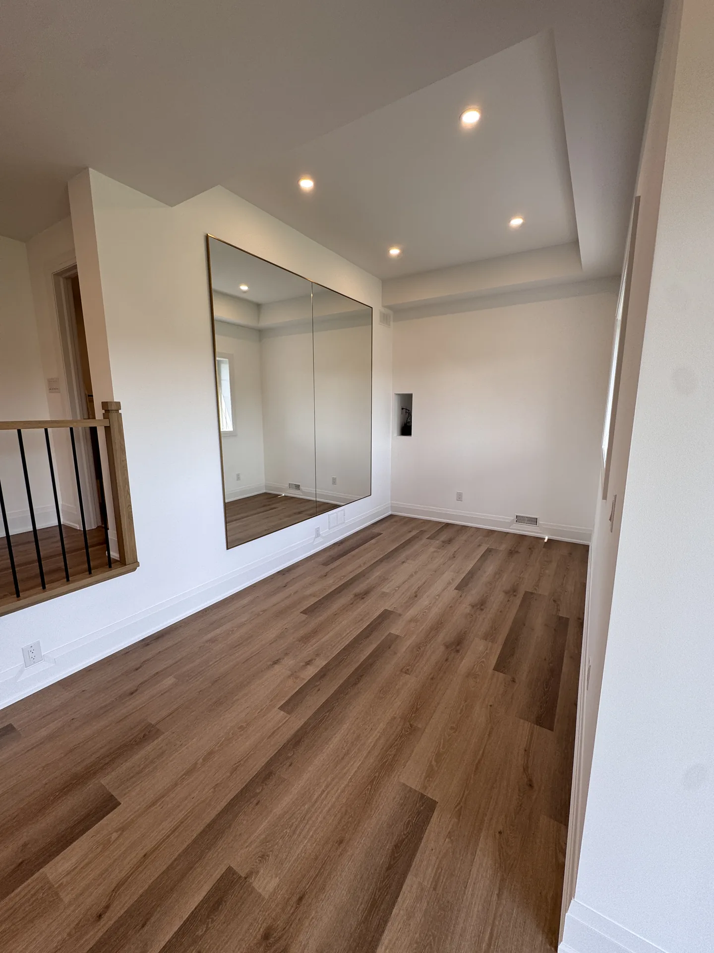 Finished basement hallway with mirror and oak floors — basement renovation in Newmarket by Desire Basements