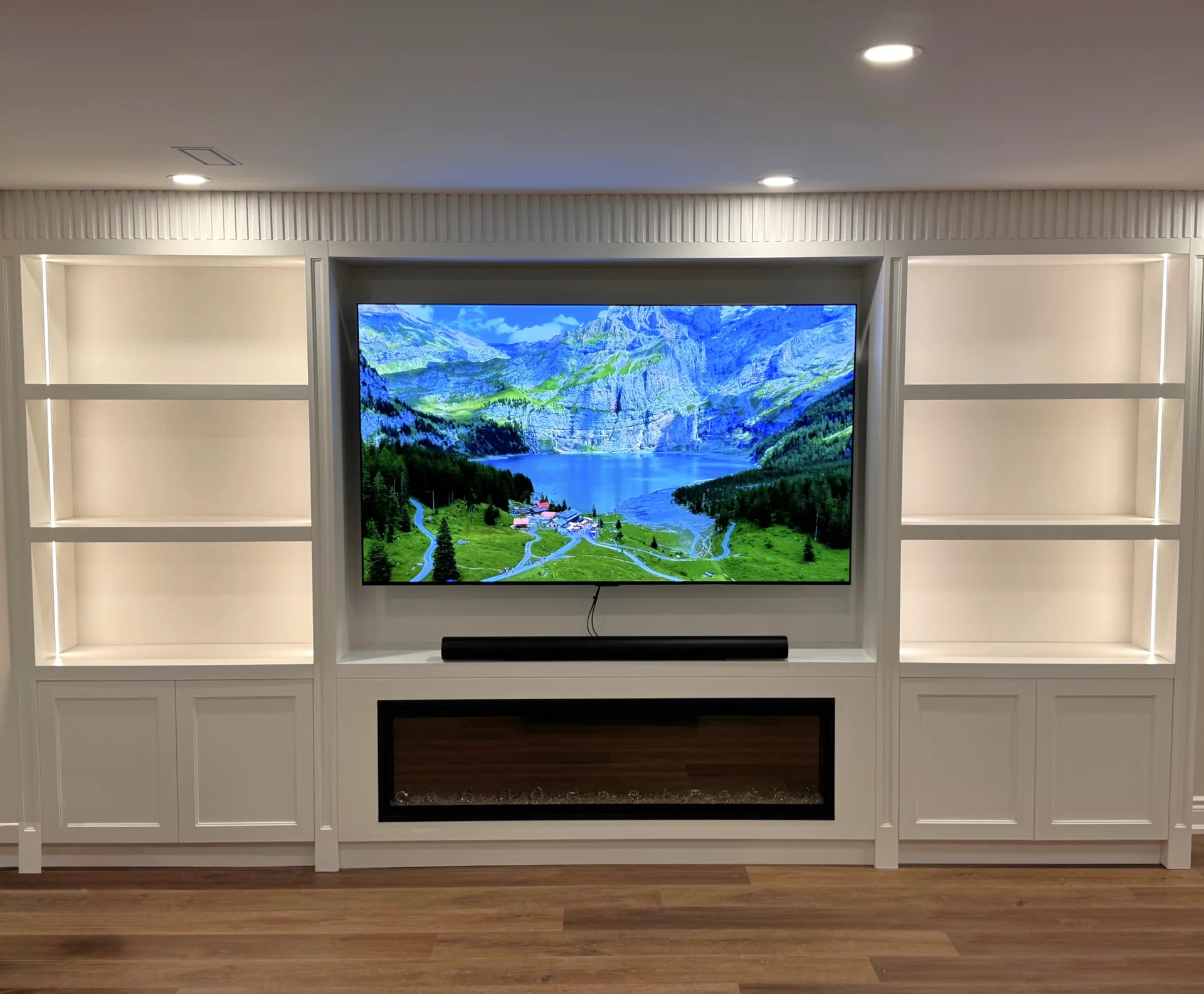 White basement TV wall with fluted panels and linear fireplace — basement renovation in Whitby by Desire Basements