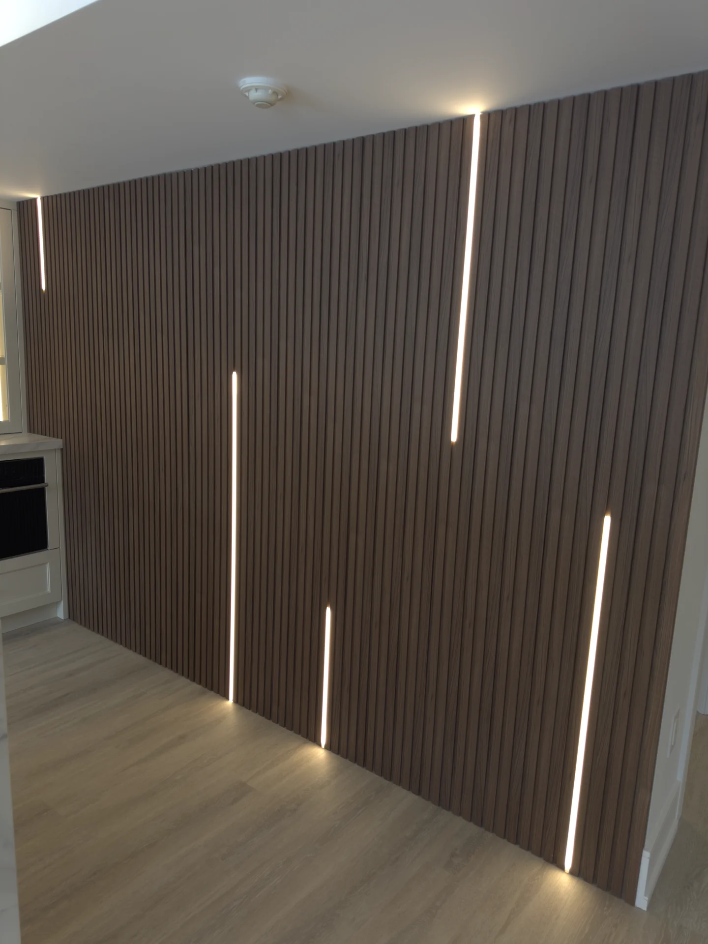 Wood slat feature wall with vertical LED strips — basement renovation in Aurora by Desire Basements