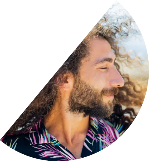 Happy man with curly hair and colourful shirt looking to the side, hair blowing in the wind, in a half circle.