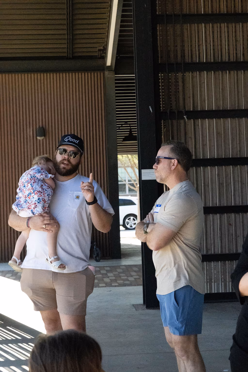 A man holding a young child while talking with another man