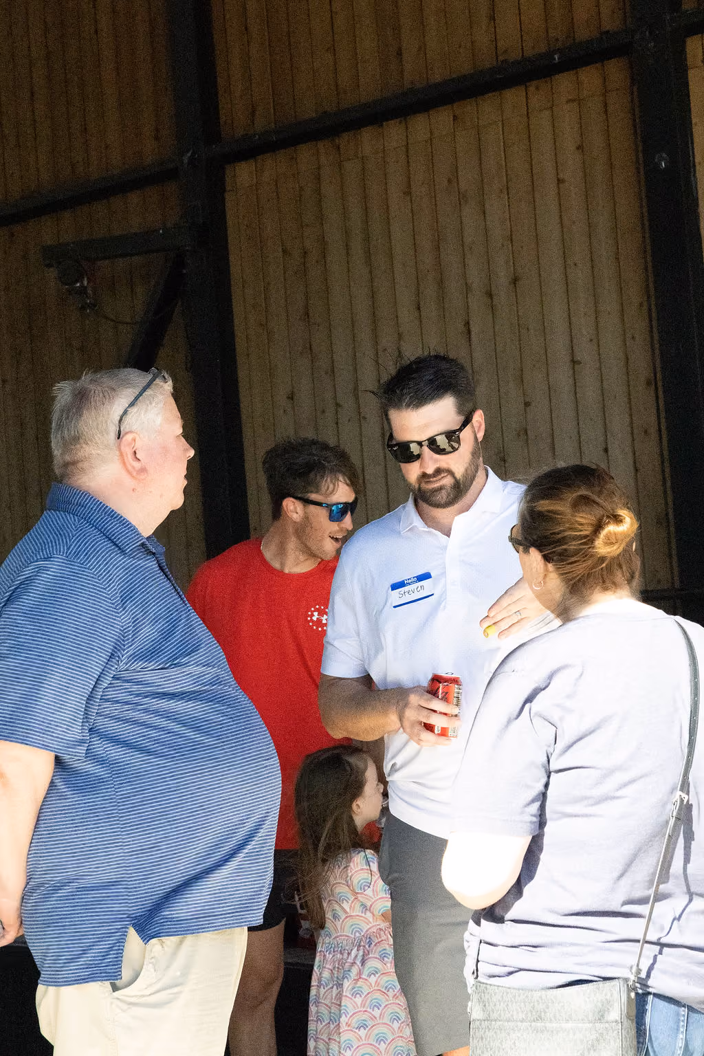 A small group talking together in a barn, with a young girl nearby