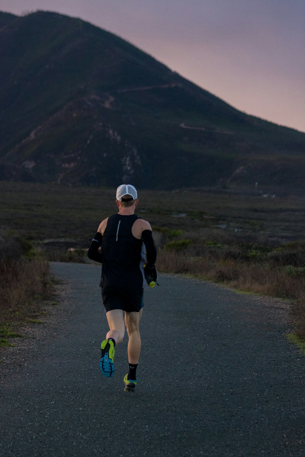 Woman jogging on a road across a mountain landscape