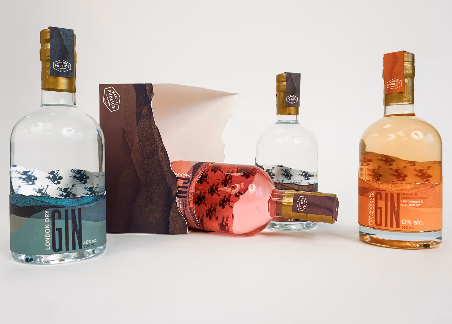 Four gin bottles with artistic labels in clear, pink, and amber tones on a white surface.