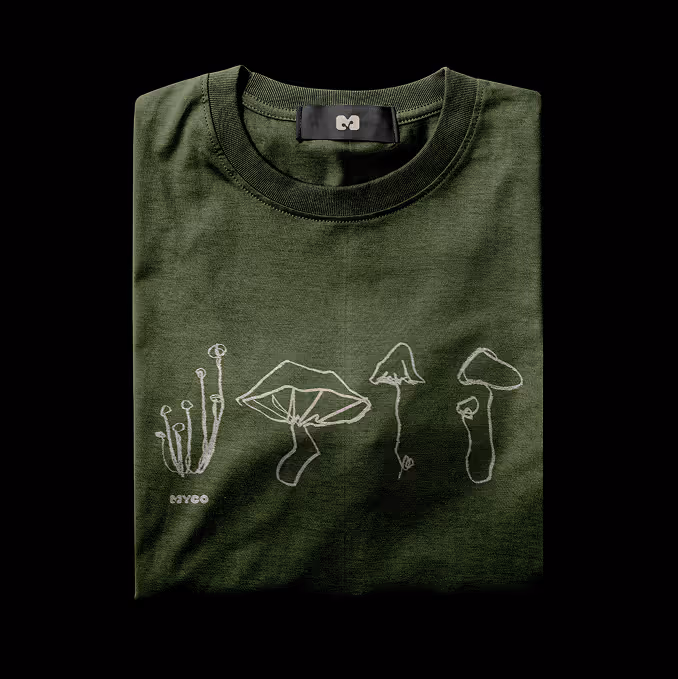 Folded olive green t-shirt with white stylized mushroom illustrations and label. (mockup.maison.com)