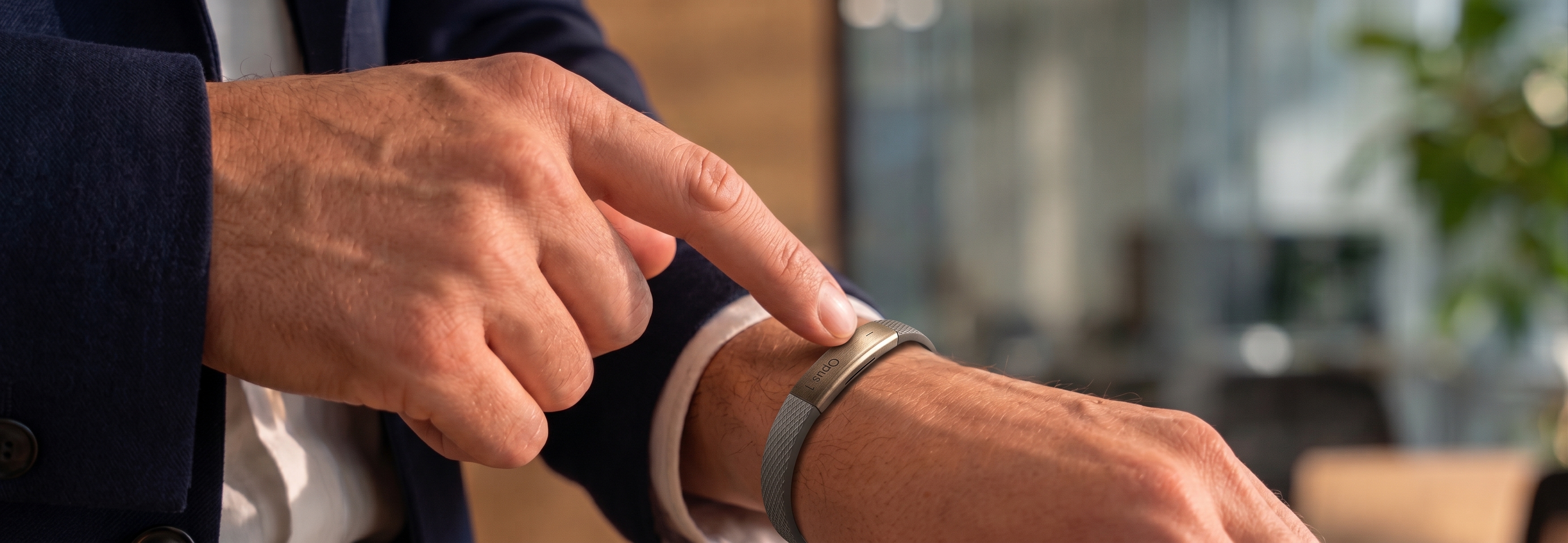 A finger pressing the button on the Nagome bracelet