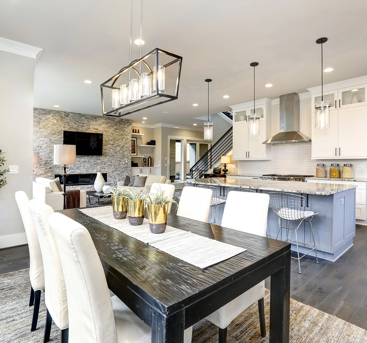 Modern open-plan kitchen and dining area with dark wood table, white chairs, and granite kitchen island.