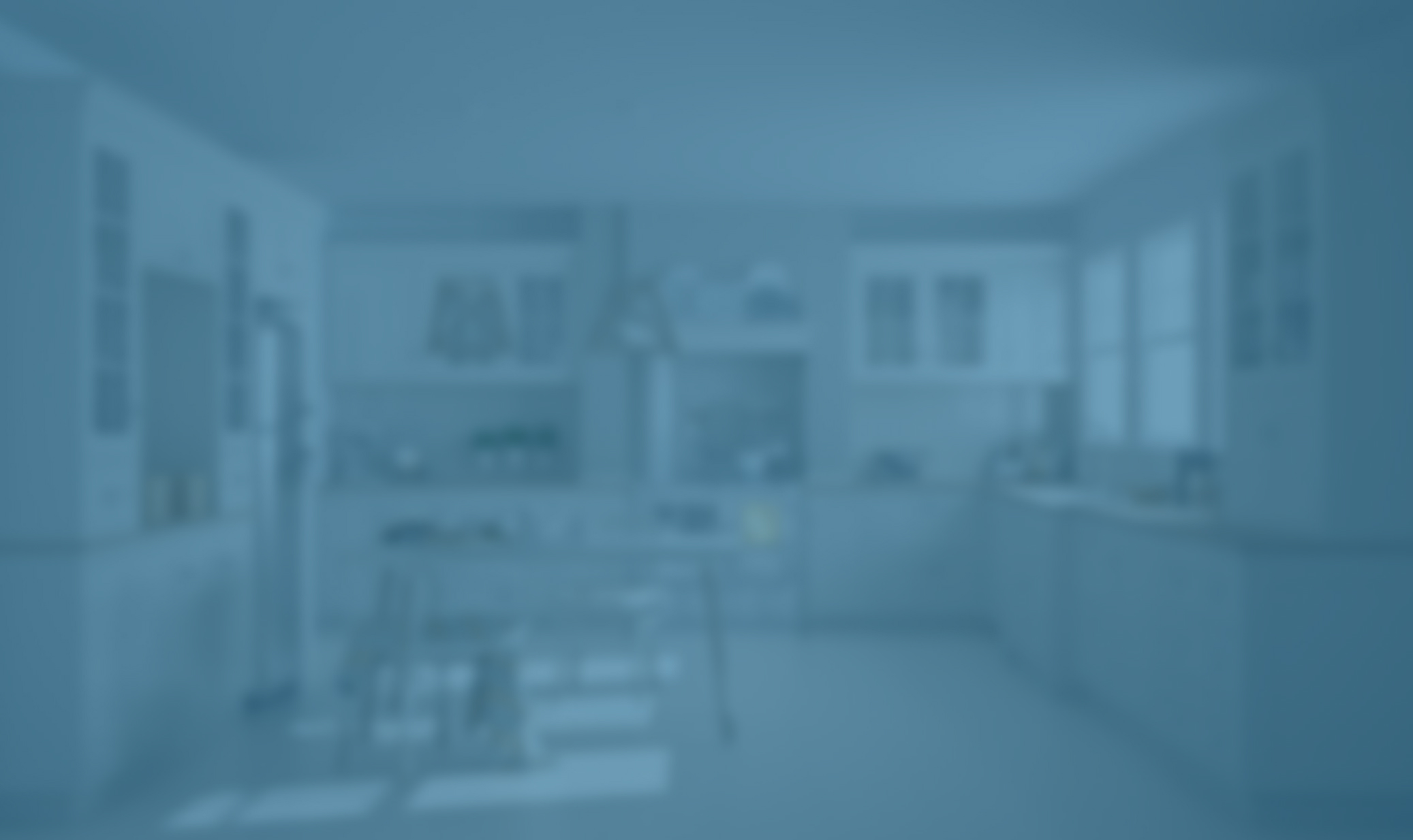 Blurry image of a modern kitchen with cabinets, appliances, dining table, and large windows.