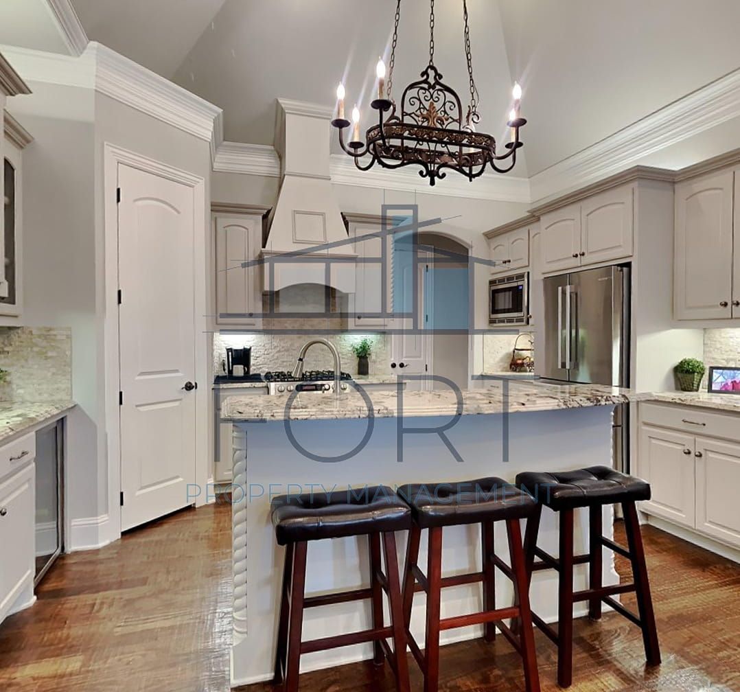 Modern kitchen with white cabinets, granite island, three bar stools, stainless steel appliances, and chandelier.
