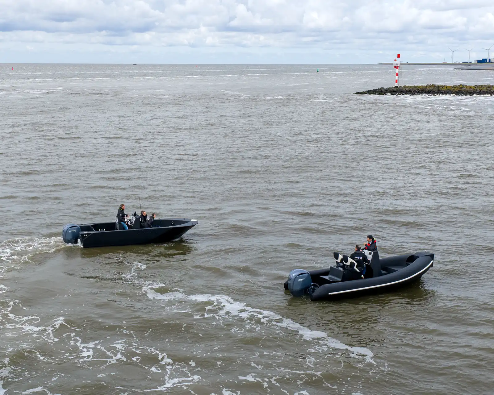 Two Dutch Boat Factory boats underway on open water beside a breakwater