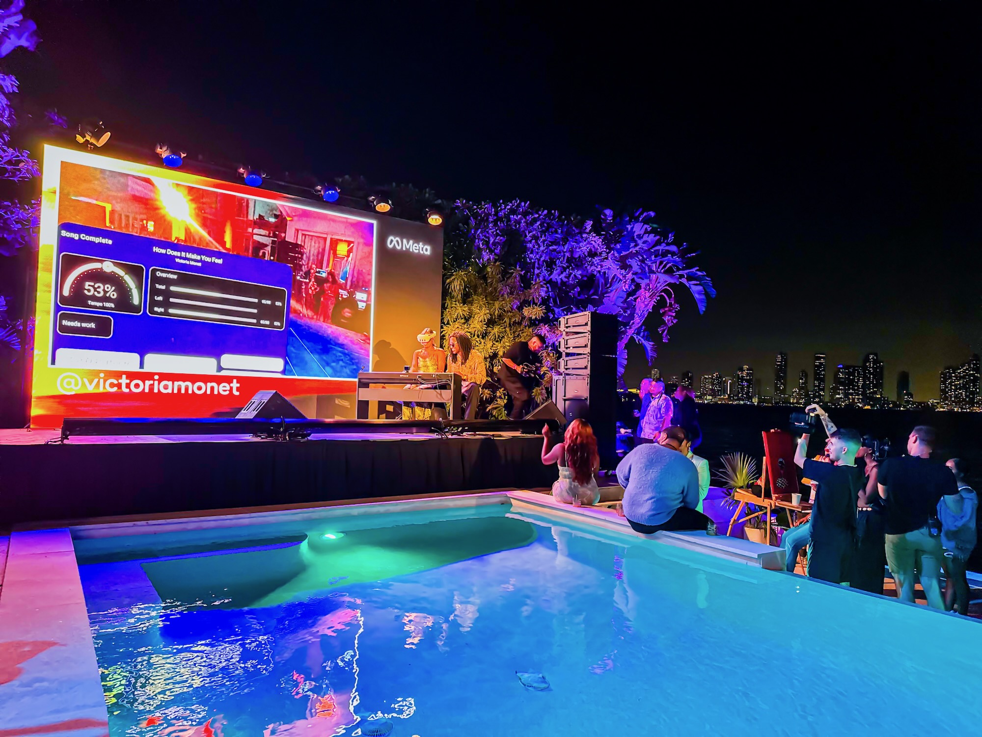 Victoria Monét performing on the pool stage at Meta's Art Basel Miami activation, with the Meta LED wall and Miami skyline behind.