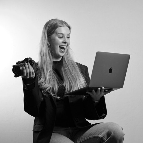 Glad person med kamera och laptop