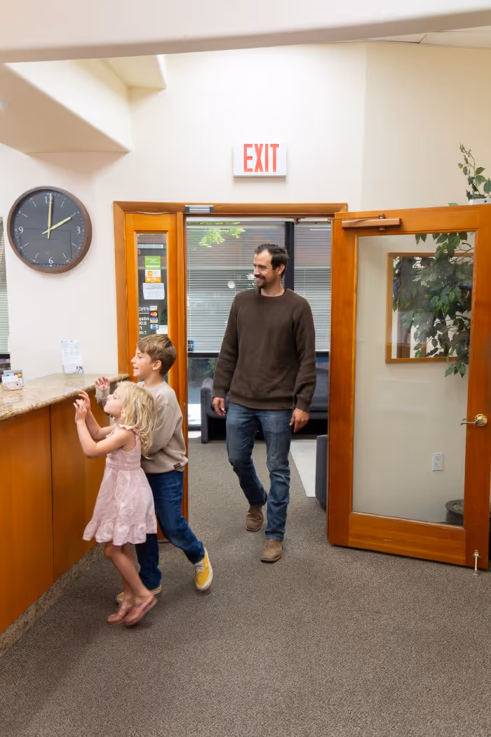 Man entering office with two children standing by the reception counter.